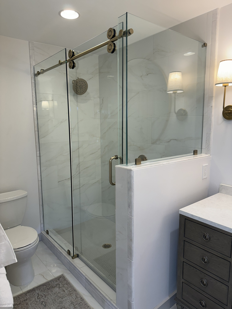 Custom bathroom remodel in Statham, GA by Encompass Contracting featuring a frameless sliding glass shower with brushed gold hardware