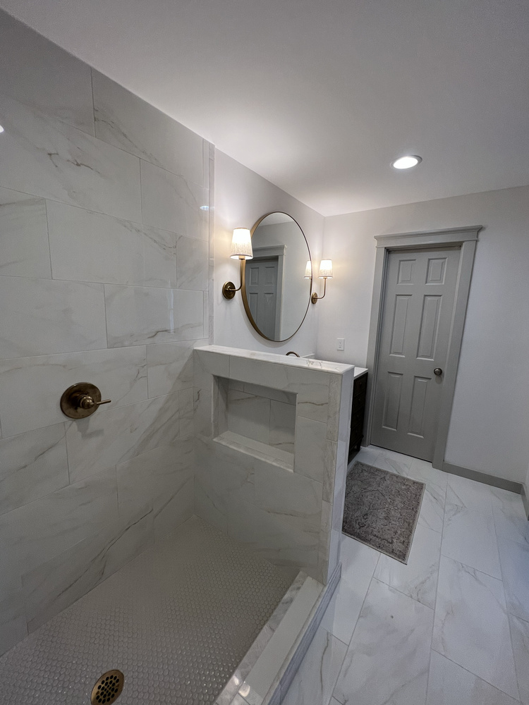 Niche shelf detail in Watkinsville, GA bathroom remodel by Encompass Contracting with marble tile and gold fixtures