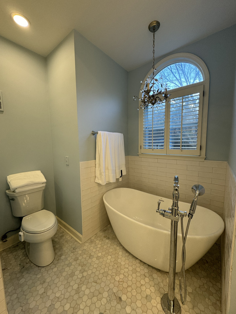 Bathroom remodel in Bishop, Georgia by Encompass Contracting with freestanding tub and chandelier under arched window