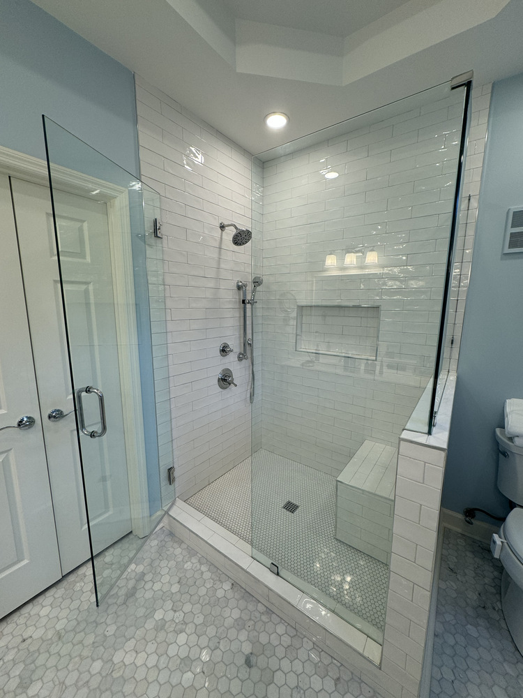 Custom shower remodel in Athens, Georgia by Encompass Contracting featuring white subway tile, glass walls, and a built-in bench