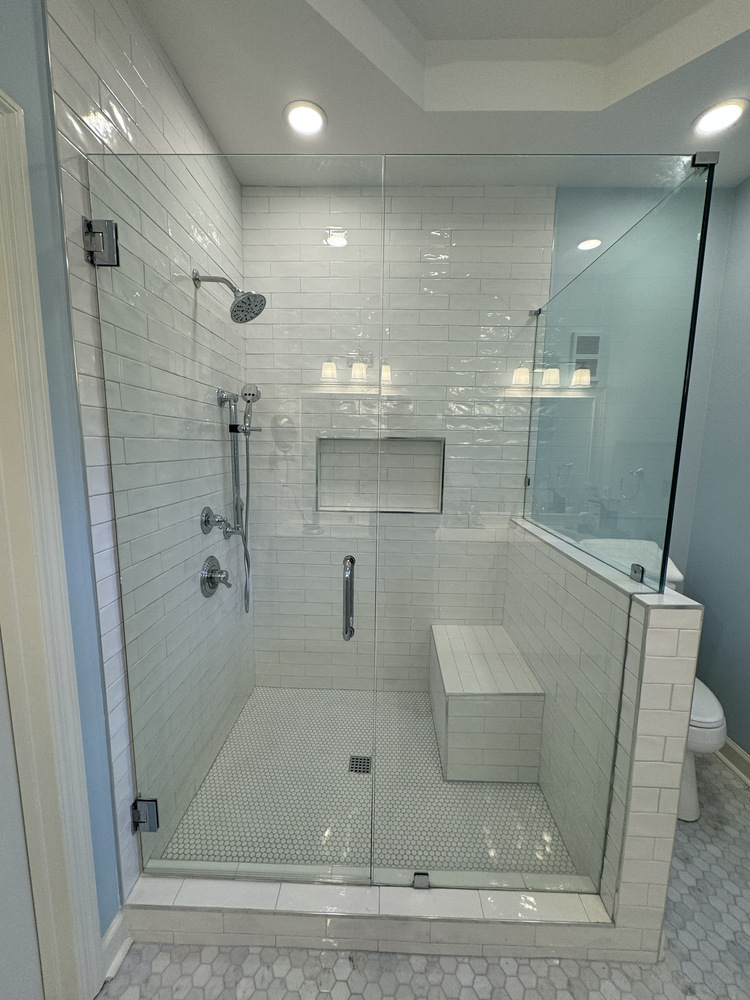 Frameless glass shower installation in Statham, Georgia by Encompass Contracting with bench seating and niche shelving
