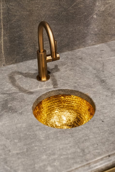 Gold vessel sink and faucet on stone vanity in Brookhaven bathroom remodel by Encompass Contracting