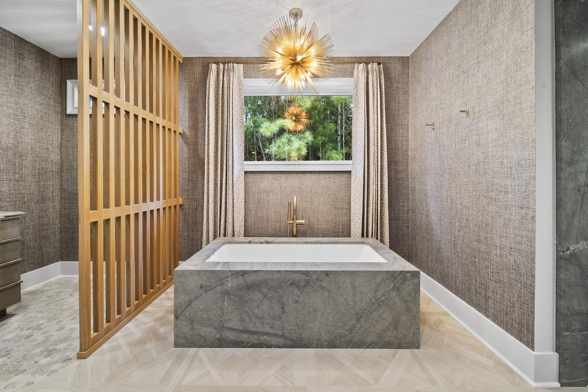 Luxury soaking tub with gold fixtures in Brookhaven bathroom remodel by Encompass Contracting