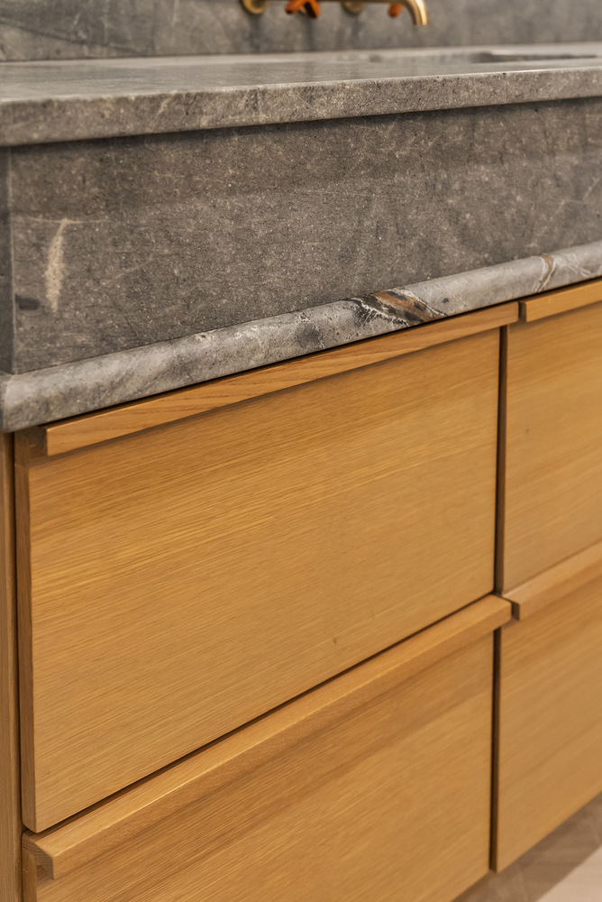 Modern stone vanity with natural wood cabinetry in Brookhaven bathroom remodel by Encompass Contracting