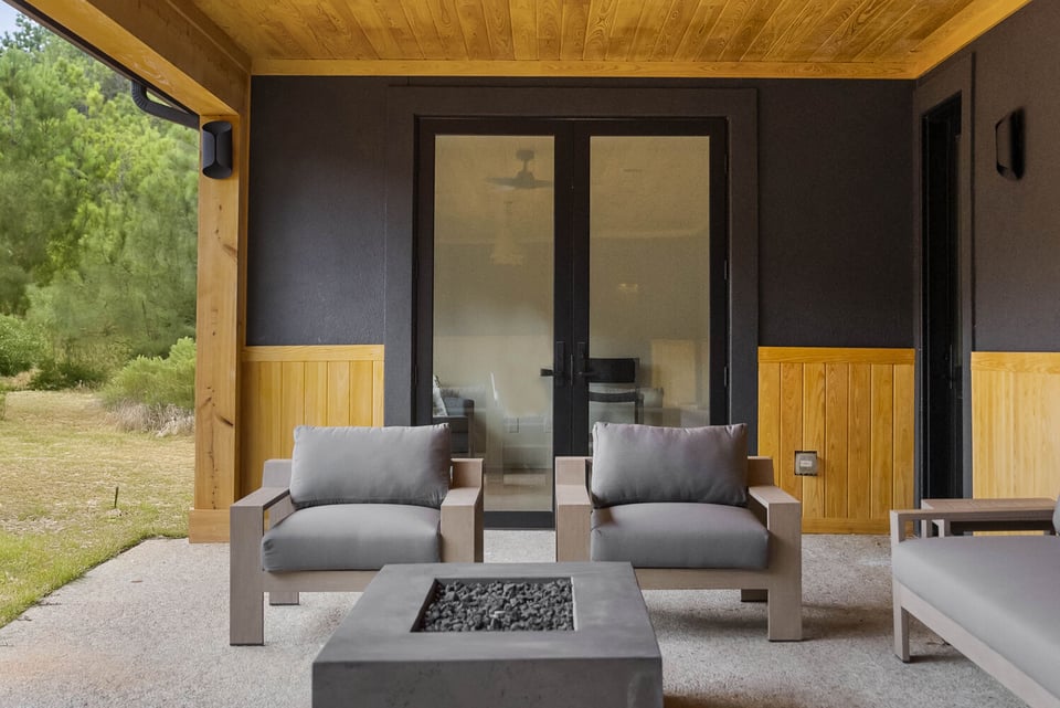 Outdoor patio seating area with modern chairs and fire pit in Brookhaven remodel by Encompass Contracting