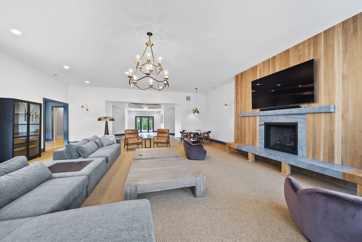Spacious Brookhaven living room remodel with custom wood fireplace and modern chandelier by Encompass Contracting