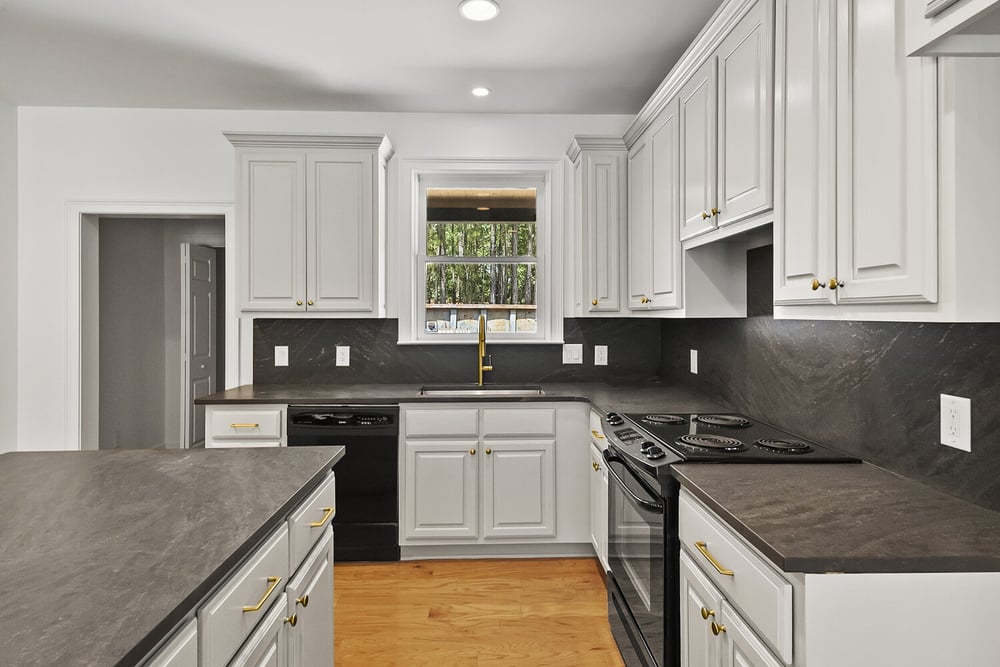 Guest kitchen with large window and gold faucet in Brookhaven remodel by Encompass Contracting