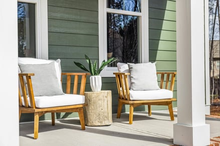 Cozy front porch remodel with wood chairs and green siding by Encompass Contracting in Athens, GA - stock
