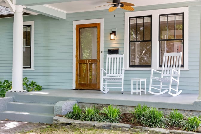 Historic porch remodel in Athens, GA with rocking chairs and wood door by Encompass Contracting - stock