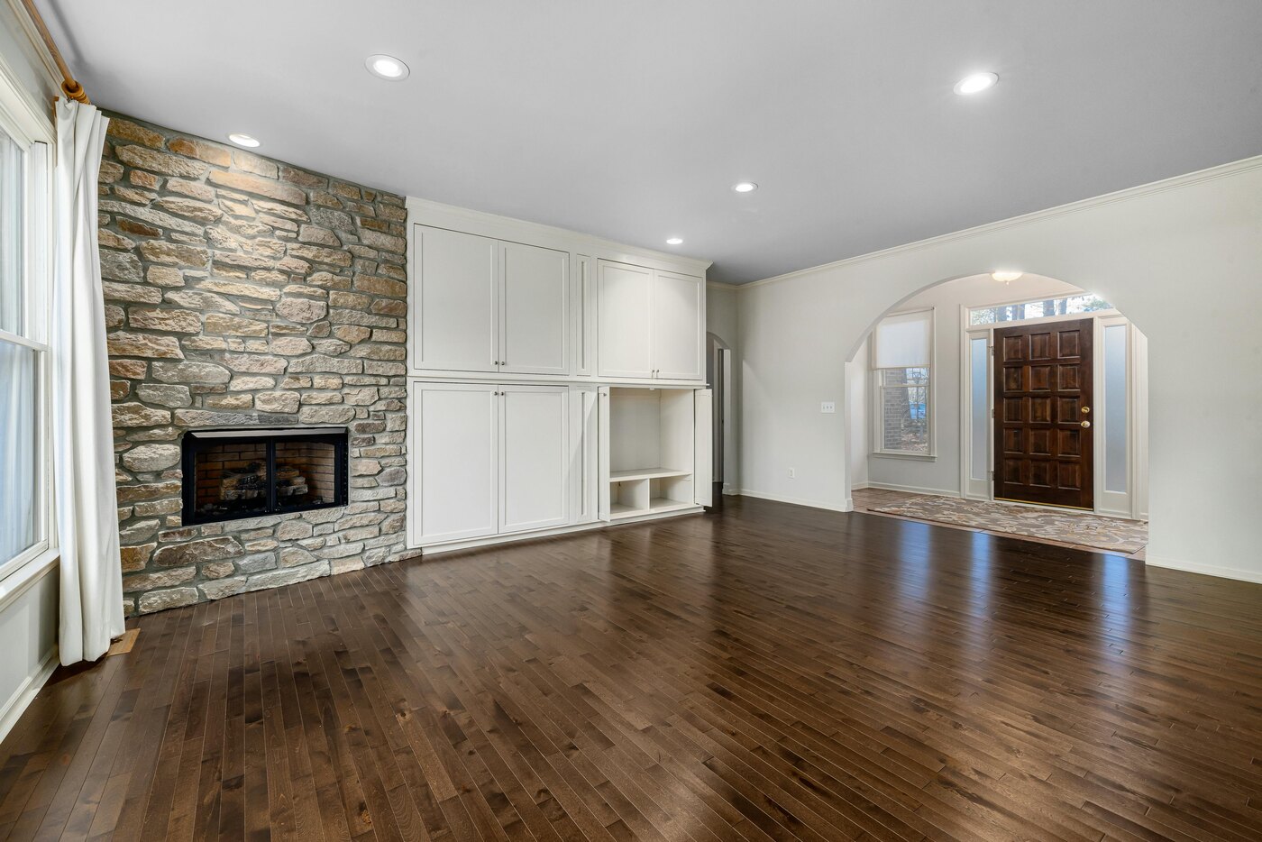 Living room remodel with a stone fireplace and hardwood floors by Encompass Contracting in Athens, GA