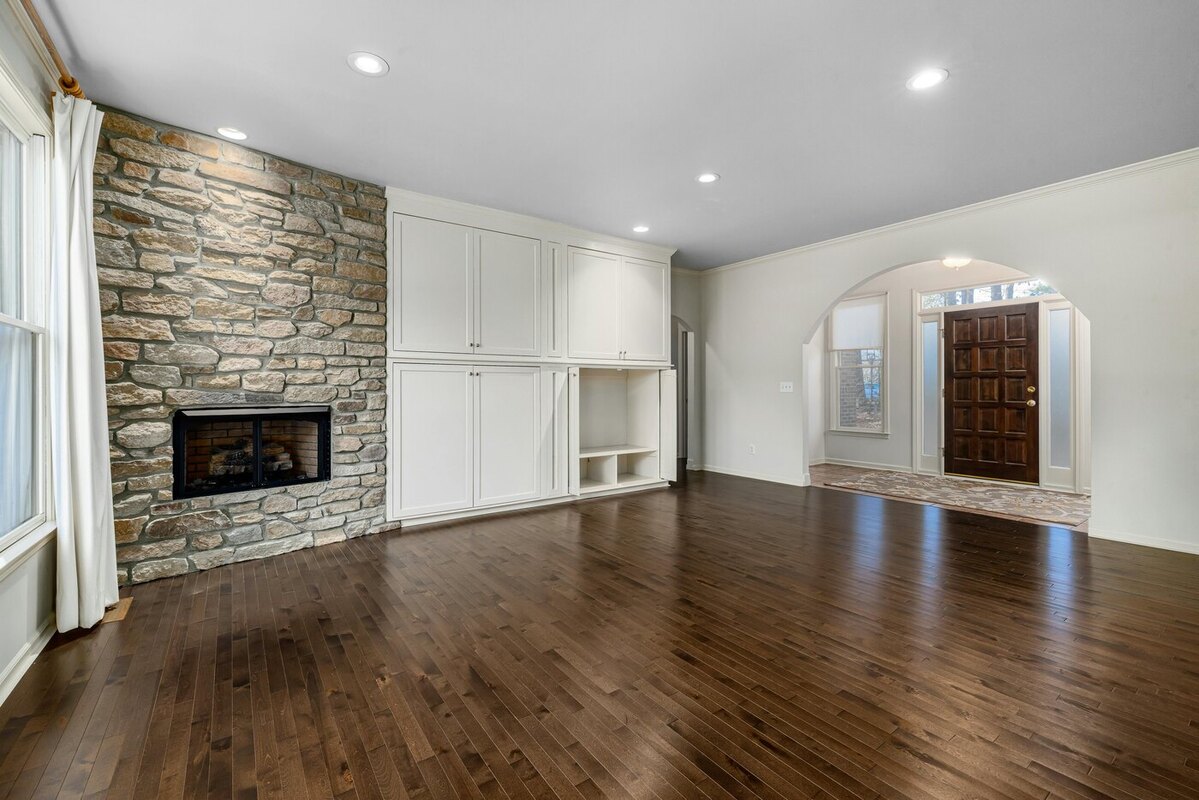Living room remodel with a stone fireplace and hardwood floors by Encompass Contracting in Athens, GA