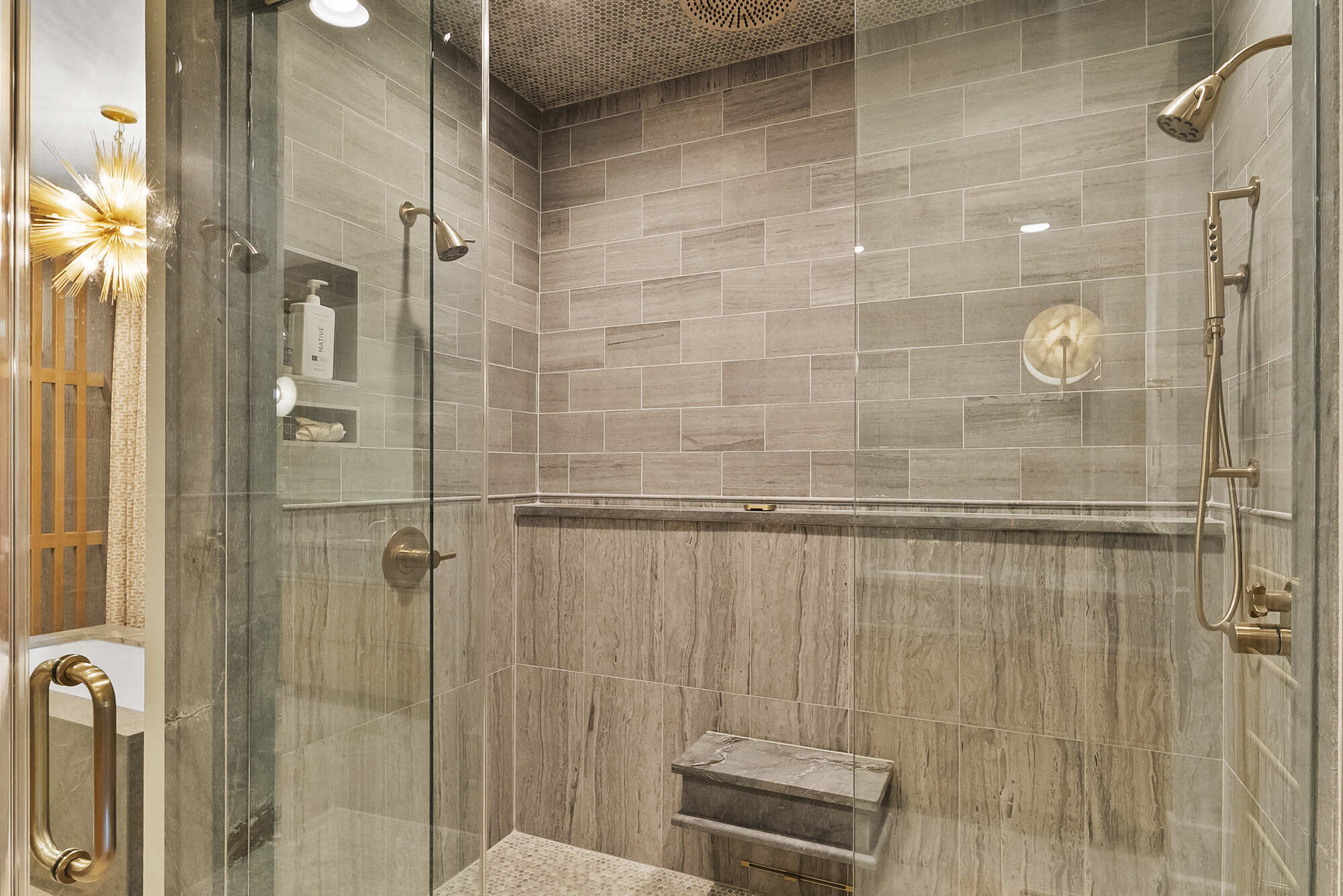 Walk-in glass shower with tile and built-in bench in Brookhaven bathroom remodel by Encompass Contracting