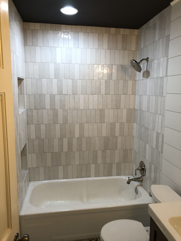 Bathroom tub and shower remodel in Statham, GA by Encompass Contracting showcasing stacked white tiles and built-in shelving
