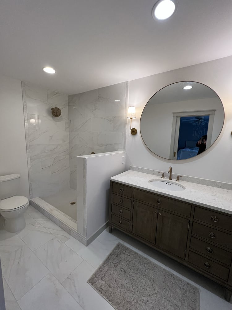 Full bathroom remodel in Athens, GA by Encompass Contracting showcasing marble tile shower and dark wood vanity