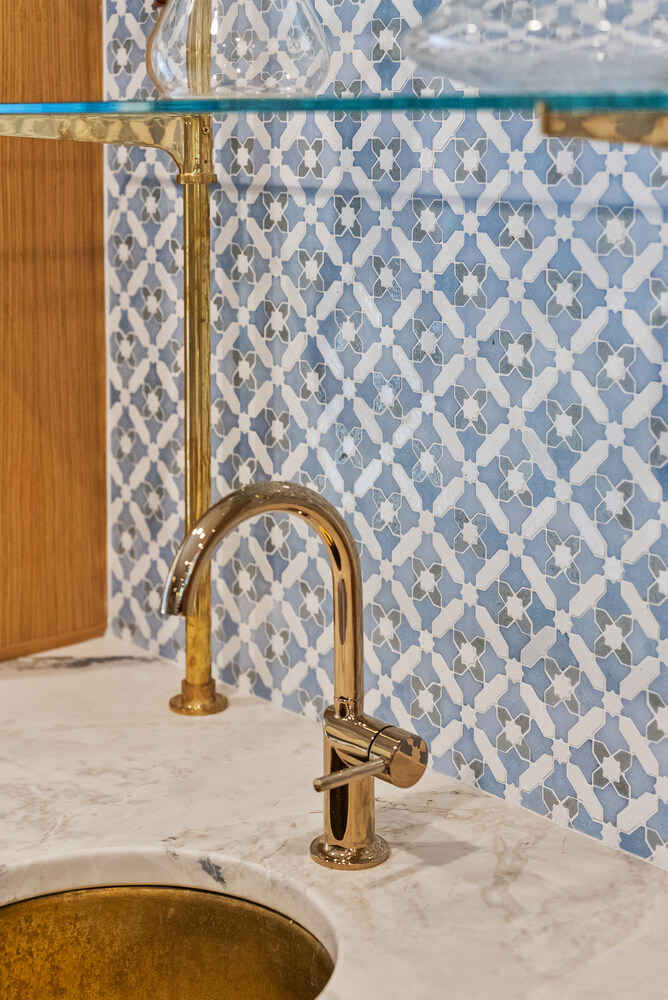 Bar sink with gold faucet and patterned blue tile backsplash in Brookhaven remodel by Encompass Contracting