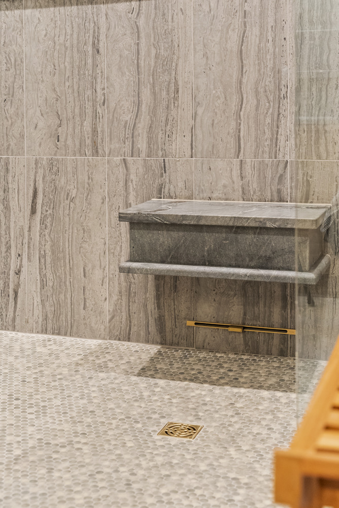 Built-in marble shower bench with tile surround in Brookhaven bathroom remodel by Encompass Contracting