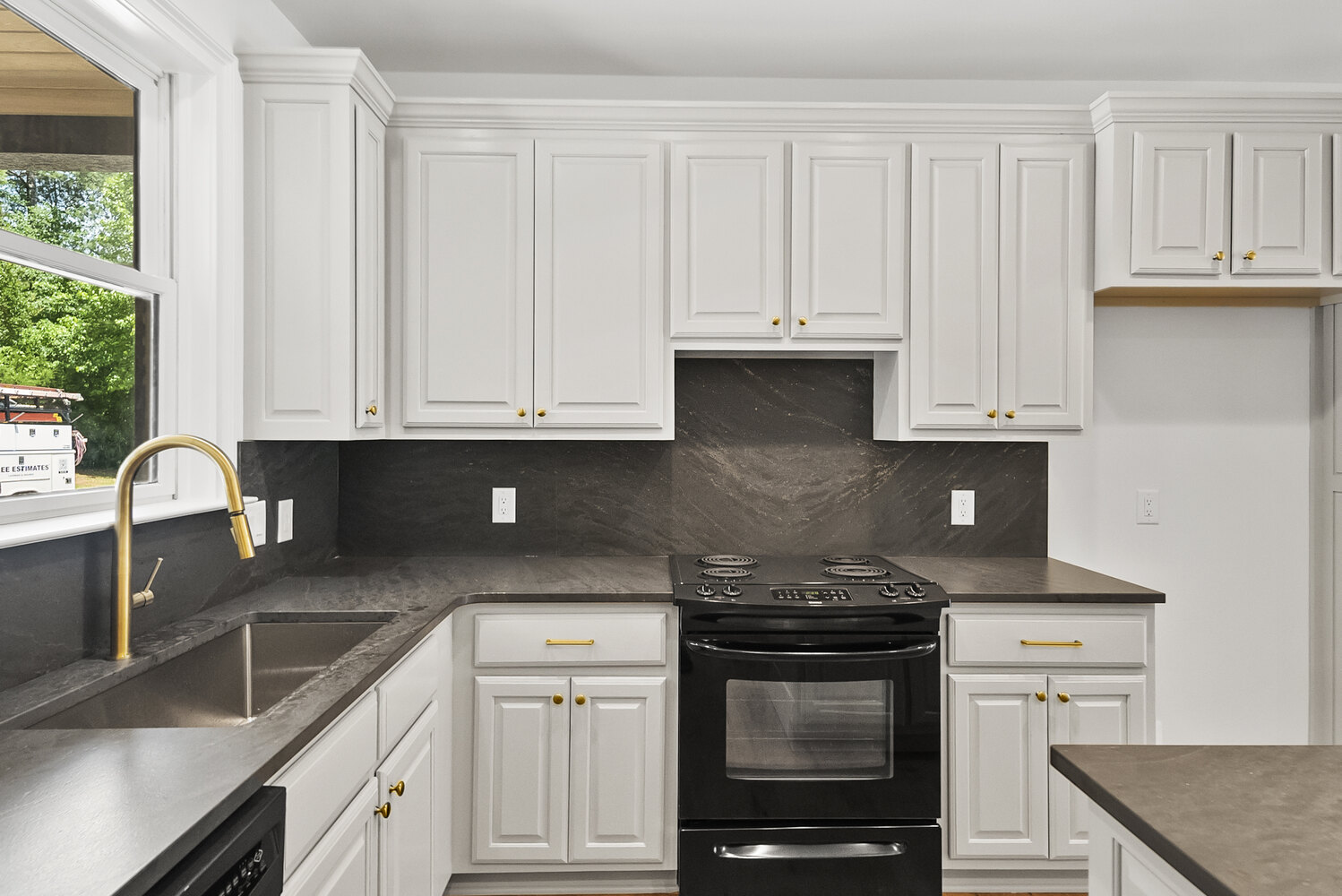 Guest kitchen with black stove and marble-style backsplash in Brookhaven remodel by Encompass Contracting